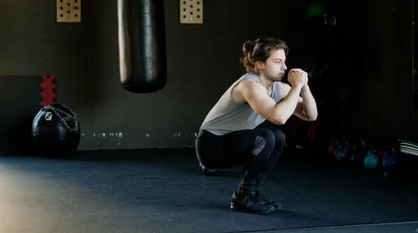 a man doing squats- a classic workout exercise to strengthen leg muscles