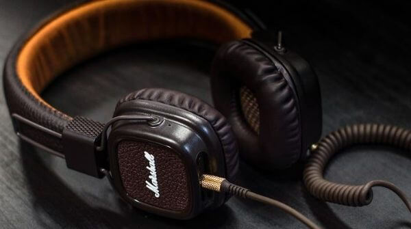 Black colored headphones shown with a wire plugged in the jack on the driver to connect to, for example, a speaker.