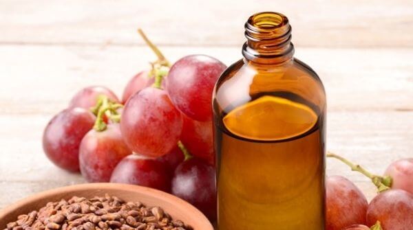a flask of grapeseed massage oil with some grapes near it.